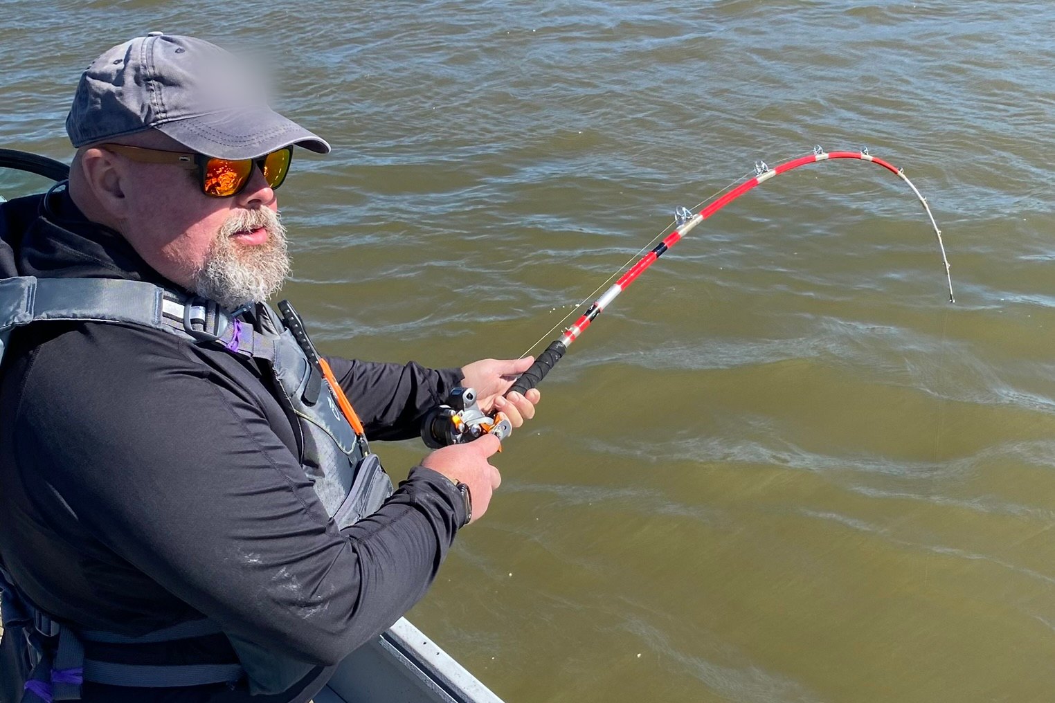 Mike fighting a fish from a boat, the rod bent hard.